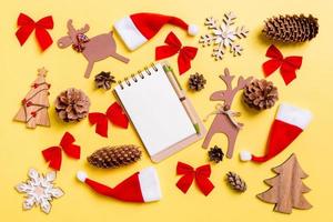 Christmas yellow background with holiday toys and decorations. Top view of notebook. Happy New Year concept photo