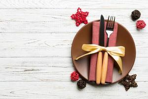 Holiday composition of Christmas dinner on wooden background. Top view of plate, utensil and festive decorations. New Year Advent concept with copy space photo