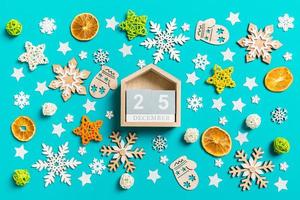 Top view of wooden calendar on blue background with New Year toys and decorations. The twenty fifth of December. Christmas time concept photo