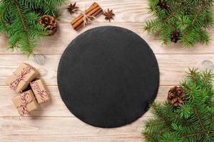 Empty Slate plate on table with christmas decoration. black slate stone on wooden background. copy space. New Year concept photo