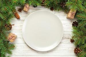 vista superior. plato vacío de cerámica redonda sobre fondo de navidad de madera. concepto de plato de cena navideña con decoración de año nuevo foto