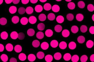Unfocused abstract pink bokeh on black background. defocused and blurred many round light photo