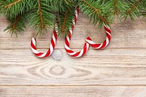 Christmas fir tree branches with candy cane on white rustic wooden background with copy space for text photo