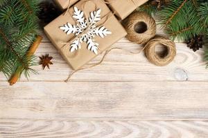 Christmas decoration elements string, chrtistmas tree branches with cones and several decorated gifts on white wooden background photo