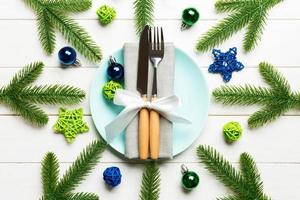 Top view of New Year dinner on festive wooden background. Composition of plate, fork, knife, fir tree and decorations. Merry Christmas concept photo