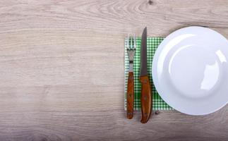 plato vacío, tenedor y cuchillo sobre fondo de madera. foto