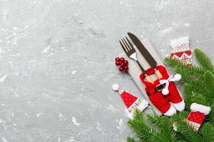 Top view of christmas decorations on cement background. Fork and knife on napkin tied up with ribbon and empty space for your design. New year pattern concept photo