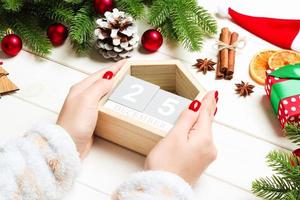 Top view of female hands holding a calendar on wooden background. The twenty fifth of December. Holiday decorations. Christmas concept photo