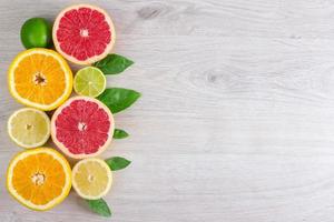 Juicy citrus fruits cut background mint leaf. Oranges, lemons, limes, grapefruit, mint leaves on a bright wooden background photo