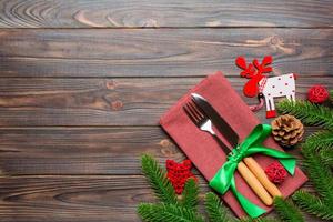 Top view of flatware tied up with ribbon on napkin on wooden background. Christmas decorations and reindeer with empty space for your design. New Year holiday concept photo