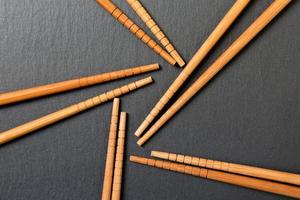 Many bamboo chopsticks on black slate background, textured, top view with opy space photo