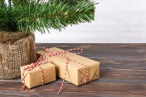 Different New Year's gifts wrapped in wrapping paper under the Christmas tree branch photo