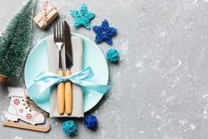 Holiday composition of Christmas dinner on cement background. Top view of plate, utensil and festive decorations. New Year Advent concept with copy space photo
