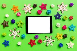 Top view of digital tablet. New Year decorations on green background. Festive stars and balls. Merry Christmas concept photo