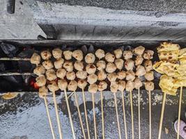 albóndigas a la parrilla. comida local tradicional de la calle en indonesia donde el proceso de fabricación se asa a la parrilla con carbón caliente foto