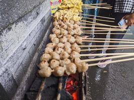 albóndigas a la parrilla. comida local tradicional de la calle en indonesia donde el proceso de fabricación se asa a la parrilla con carbón caliente foto