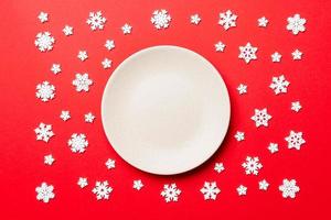 Top view of empty plate surrounded with snowflakes on colorful background. New Year dinner concept photo