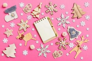 Top view of notebook on pink background made of holiday decorations and toys. Christmas ornament concept photo