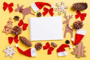 fondo amarillo navideño con juguetes y decoraciones navideñas. vista superior del cuaderno. feliz año nuevo concepto foto