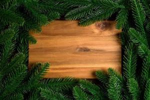 Top view of wooden plate decorated with fir tree branches. New Year dinner concept with empty space for your design photo