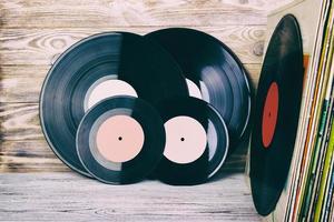 Retro styled image of a collection of old vinyl record lp's with sleeves on a wooden background with Copy space top view toned photo