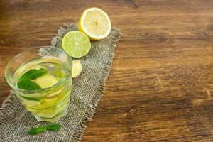 Ginger ale soda with lemon, mint, ginger and ice over rustic wooden background photo