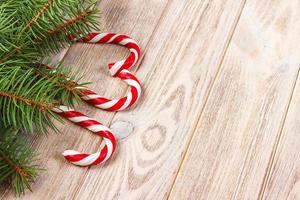 Christmas tree branch and candy cane on a wooden table or board for background. New year theme. Space for text photo