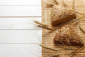 Several small multi grain triangular shaped bread sprinkled with whole sunflower seeds, flax and sesame seeds and wheat and barley spikes photo