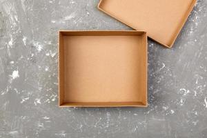 Empty opened brown cardboard box for mock up on gray cement table with copy space photo