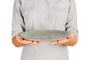 girl in the plaid shirt is holding an empty round green plate in front of her. woman hand hold empty dish for you desing. perspective view, isolated on white background photo