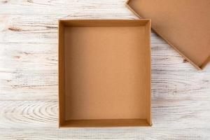 Opened empty cardboard box on wooden background. Top view photo