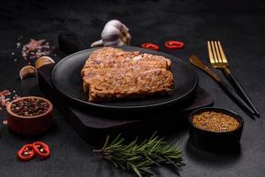 Tasty meat brawn or roll on a wooden cutting board with spices and herbs photo