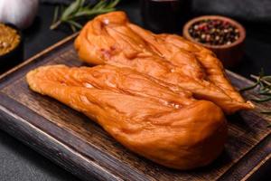 Tasty smoked fillet of chicken breast with spices and herbs on a wooden cutting board photo