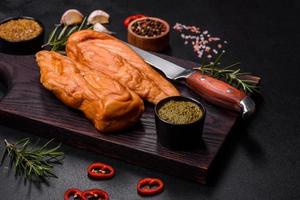 Tasty smoked fillet of chicken breast with spices and herbs on a wooden cutting board photo