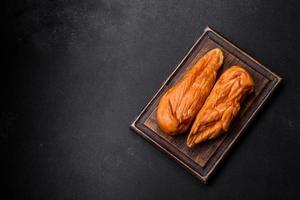 Tasty smoked fillet of chicken breast with spices and herbs on a wooden cutting board photo