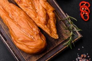 Tasty smoked fillet of chicken breast with spices and herbs on a wooden cutting board photo