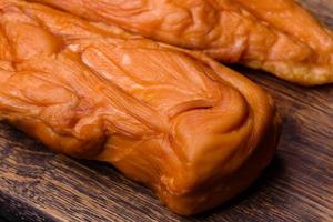 Tasty smoked fillet of chicken breast with spices and herbs on a wooden cutting board photo