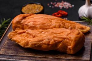 Tasty smoked fillet of chicken breast with spices and herbs on a wooden cutting board photo