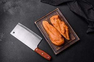 Tasty smoked fillet of chicken breast with spices and herbs on a wooden cutting board photo