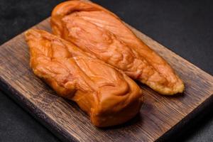 Tasty smoked fillet of chicken breast with spices and herbs on a wooden cutting board photo