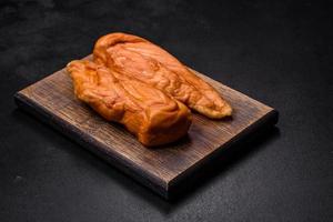 Tasty smoked fillet of chicken breast with spices and herbs on a wooden cutting board photo