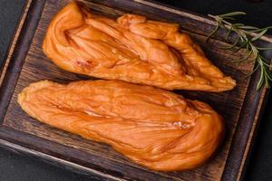 Tasty smoked fillet of chicken breast with spices and herbs on a wooden cutting board photo