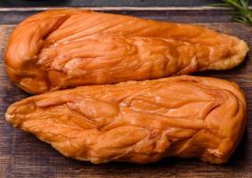 Tasty smoked fillet of chicken breast with spices and herbs on a wooden cutting board photo