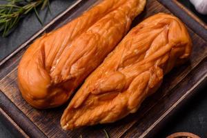 Tasty smoked fillet of chicken breast with spices and herbs on a wooden cutting board photo