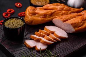 Tasty smoked fillet of chicken breast with spices and herbs on a wooden cutting board