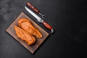 Tasty smoked fillet of chicken breast with spices and herbs on a wooden cutting board photo