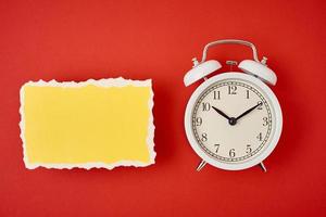 White vintage classic alarm clock with bells and empty torn paper sheet photo