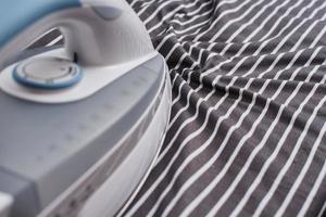 Modern iron on the ironing board, close up photo