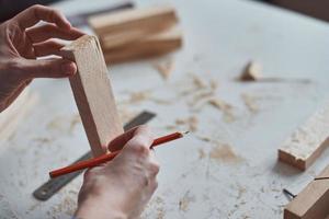 Carpenter hands taking measurement with a pencil of wooden plank. photo