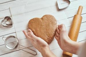 mujer amasa masa con las manos en la cocina foto